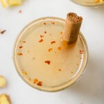 Top down image of metabolism boost drink i a glass of water. There is sliced ginger and lemon laid in the background.