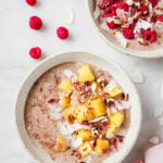 top down image of the quinoa porridge in a bowl, topped with mango