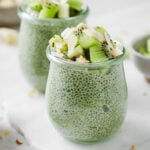 matcha chia pudding in a small pot and topped with kiwi and toasted coconut shavings