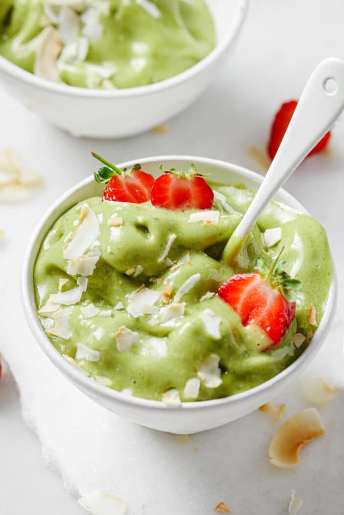 matcha nice cream in a white bowl that's slightly melty with a spoon in the center
