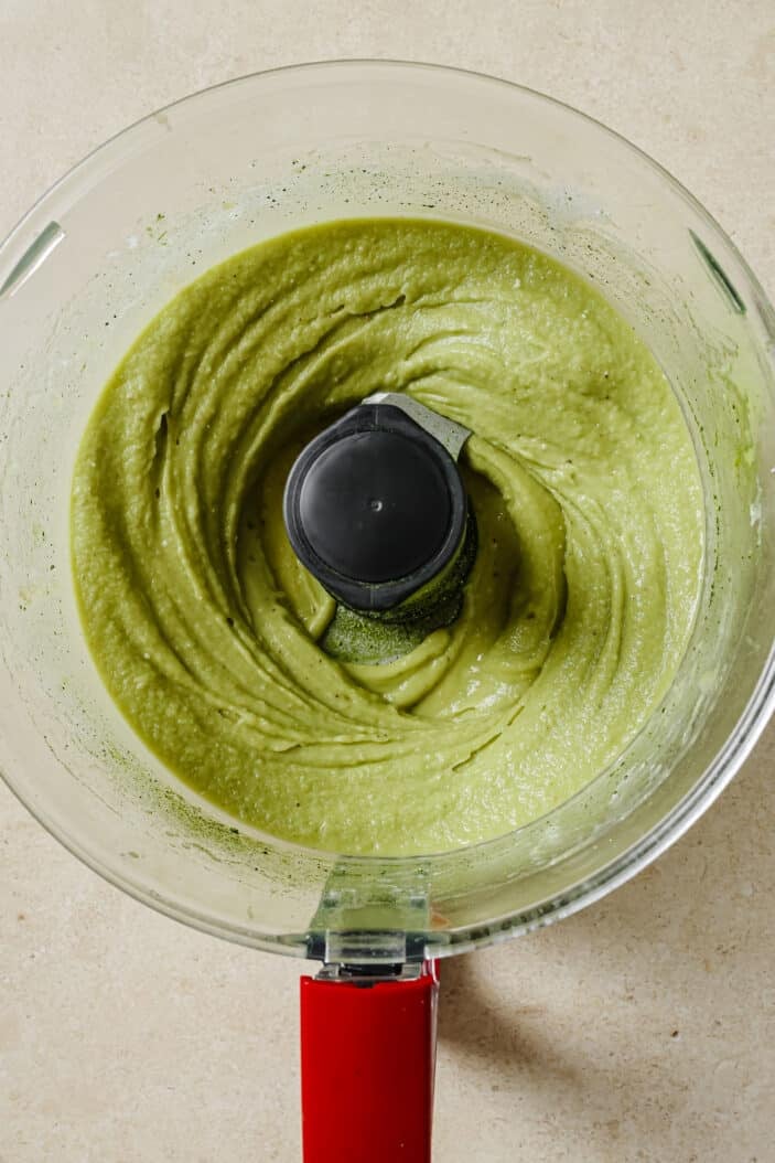 frozen bananas blended together with coconut milk and matcha to make matcha nice cream in a food processor