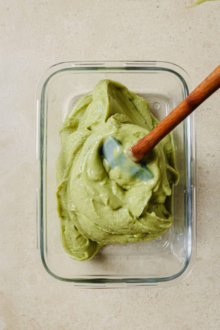 matcha nice cream that's been scooped into a glass container with a spatula