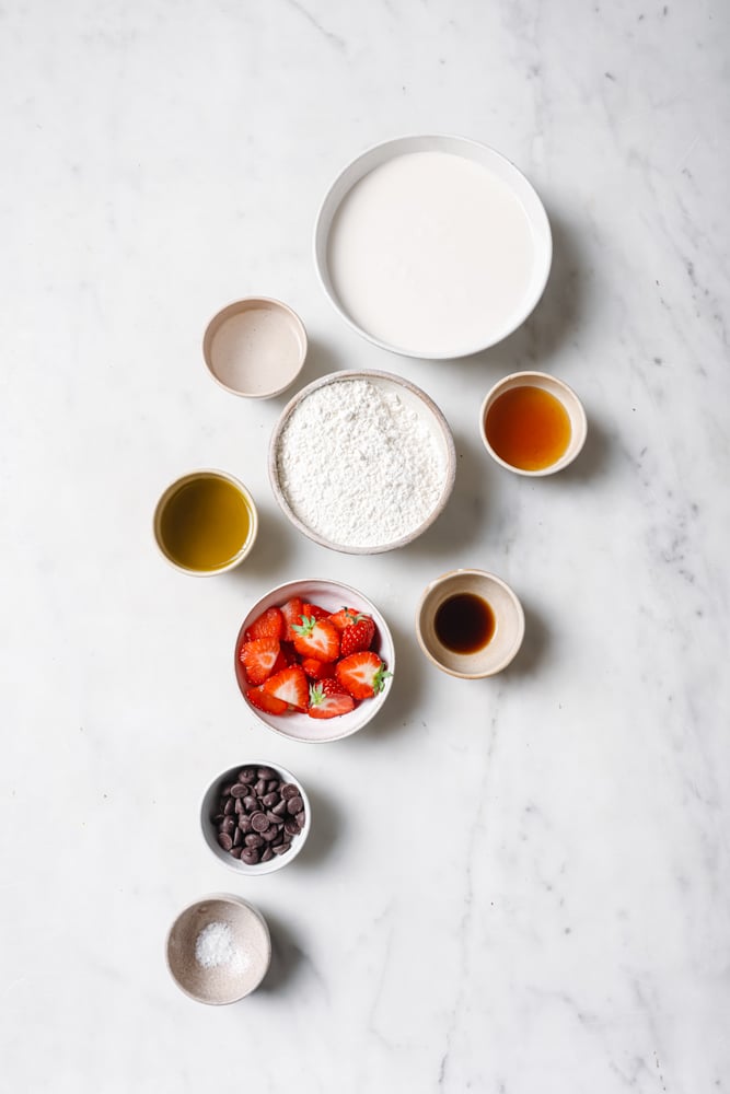 All of the ingredients required to make this vegan crepe recipe separated into individual bowls. The bowls are sitting on a white backdrop.