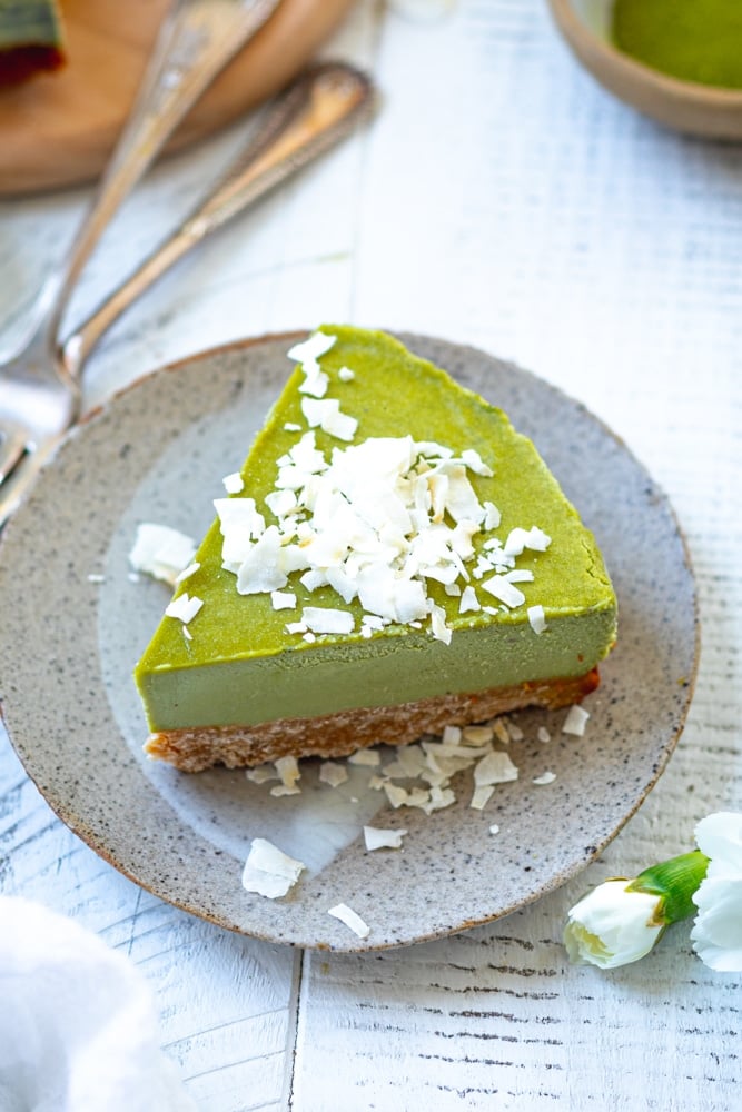 slice of vegan matcha cheesecake with coconut flakes spinkled on top