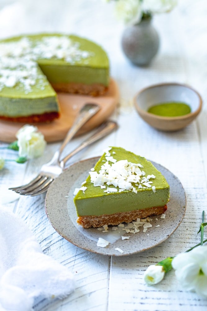 matcha cheesecake with a slice cut out and the slice on a small plate in front.