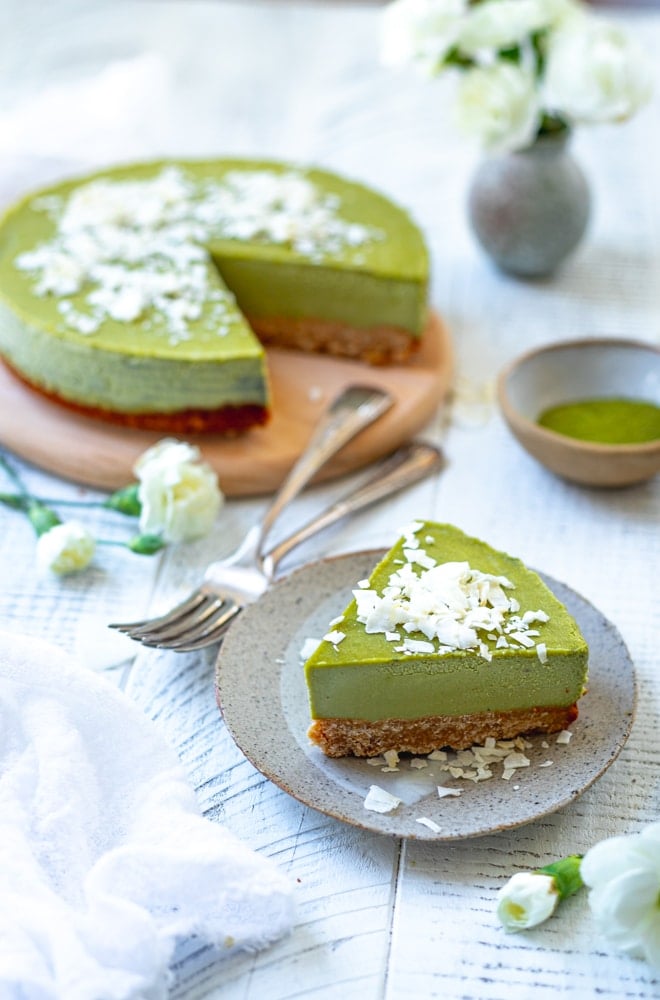 matcha cheesecake with a slice cut out and the slice on a small plate in front.