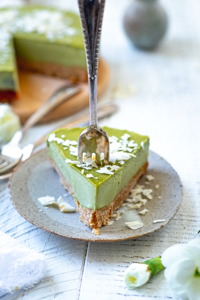 slice of matcha cheesecake with a silver fork taking out a piece
