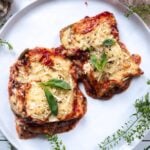 gluten-free zucchini lasagna cut into sqaures and places on a white plate. Topped with fresh basil.