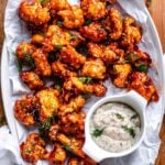 cauliflower wings on a plate being served with ranch dip and sprinkled with some fresh dill