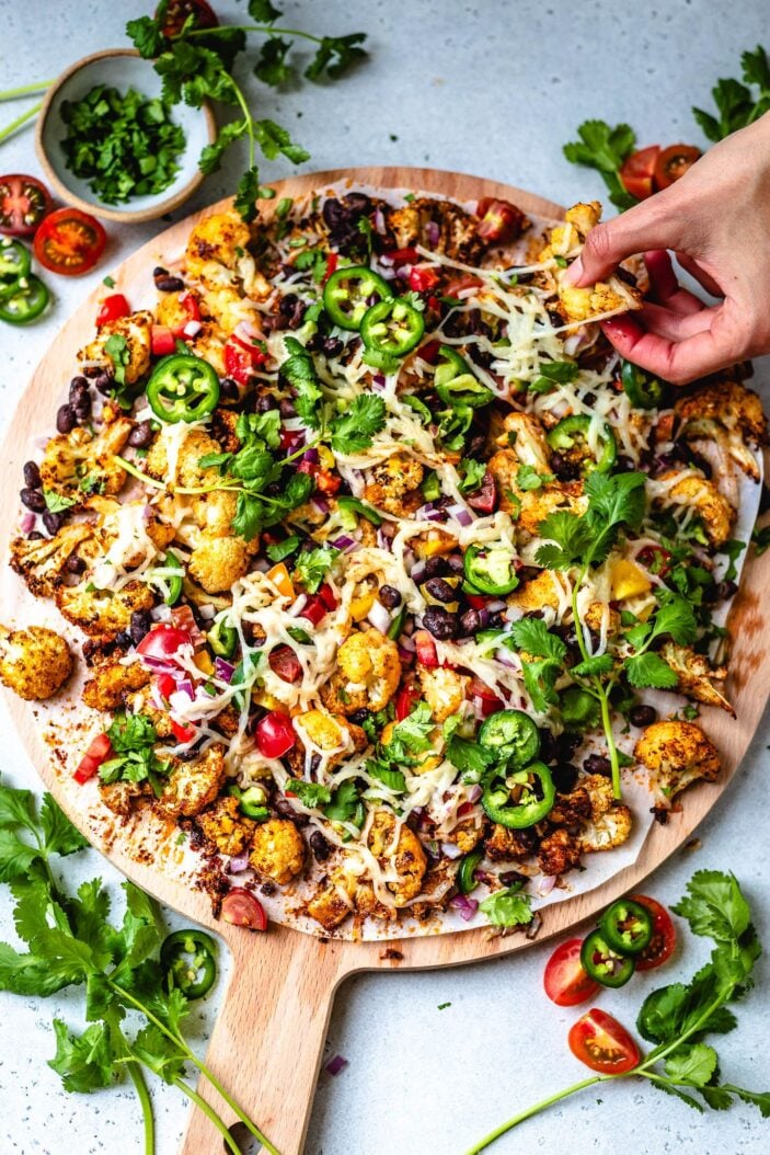 cauliflower nachos on a cutting board ready to be eaten.
