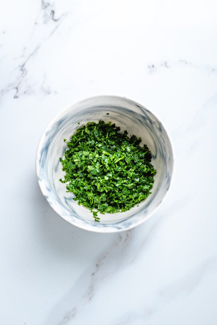 Freshly chopped herbs added to a bowl.
