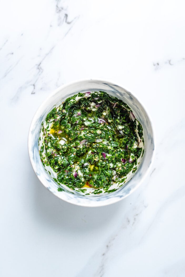 Oil added to the herb mixture and stirred together in a bowl.