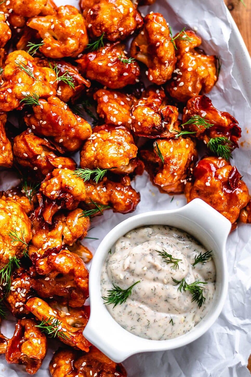 cauliflower wings on a plate being served with ranch dip and sprinkled with some fresh dill