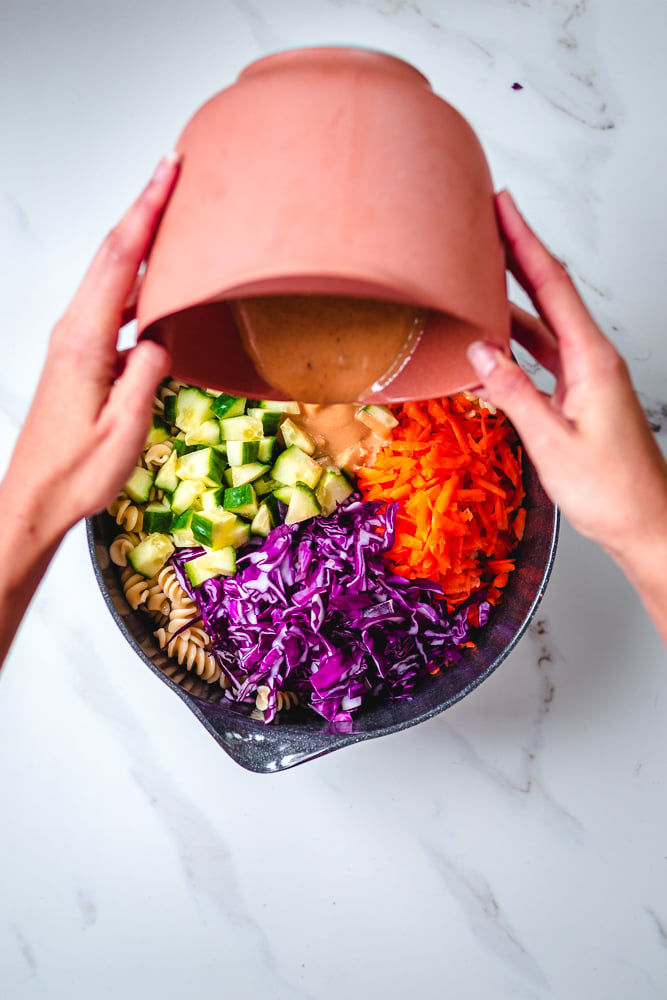 image of vegan thai peanut sauce being drizzled over a noodle bowl