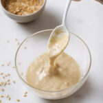 flax egg in a clear bowl being scooped with a spoon to show eggy consistency