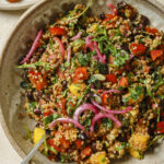 close up of black bean and quinoa salad with mango and avocado in a grey bowl with a fork inside of the bowl