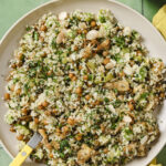 Roasted artichoke chickpea salad served on a white plate with a fork in it. The plate is on a green back drop with a yellow kitchen towel in the bottom corner.